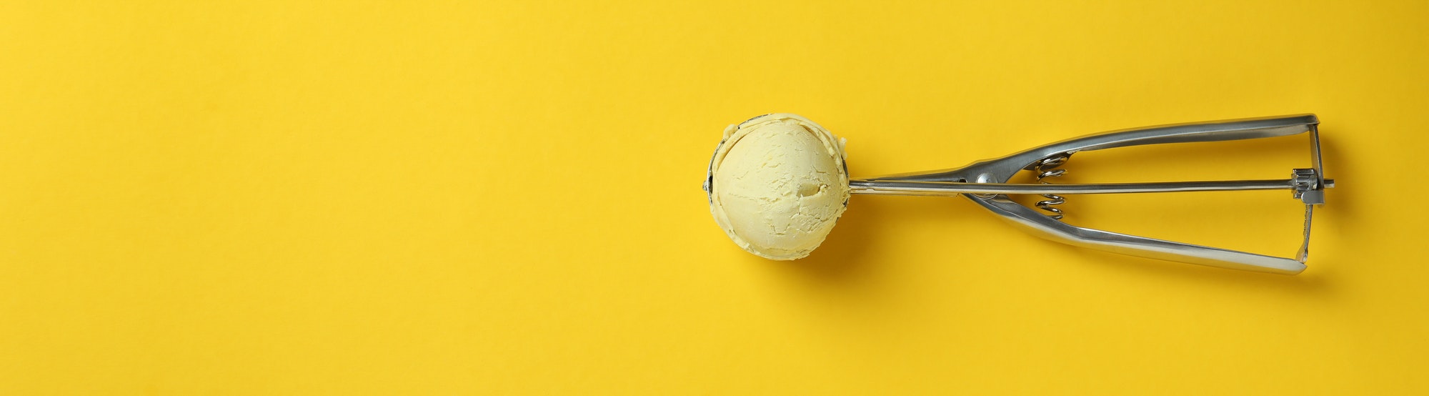 Scoop with ice cream on yellow background